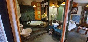Une salle de bain avec une baignoire, deux lavabos, un miroir et un banc en bois.