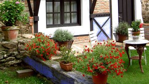A traditional half-timbered house with multiple balconies adorned with potted plants and flowers. - Camino Real de Selores (Valle de Cabuerniga)