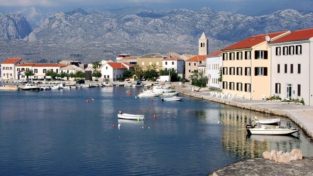 A coastal town with a marina, buildings with red roofs, and a mountain backdrop. - Beach Apartement - Studio Apartement - 2 Persons (Posedarje)