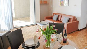 A dining area with a table set for two, a sofa, and a sliding glass door leading to an outdoor area. - Beautiful apartment for 3 guests with WIFI, TV, balcony, pets allowed and panoramic view (Sorengo)