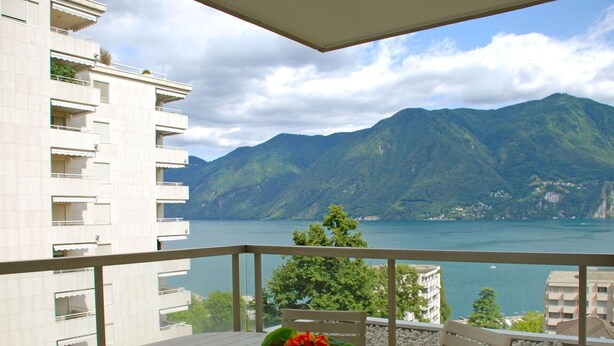 A balcony with a table and chairs, overlooking a lake and mountains. - Beautiful apartment for 3 guests with WIFI, TV, balcony, pets allowed and panoramic view (Sorengo)