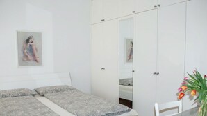 A bedroom with a bed, a mirror, a table with a vase of flowers, and a painting on the wall. - Beautiful apartment for 3 guests with WIFI, TV, balcony, pets allowed and panoramic view (Sorengo)