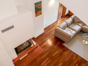 Un salon moderne avec un plancher en bois, un canapé beige et une cheminée.