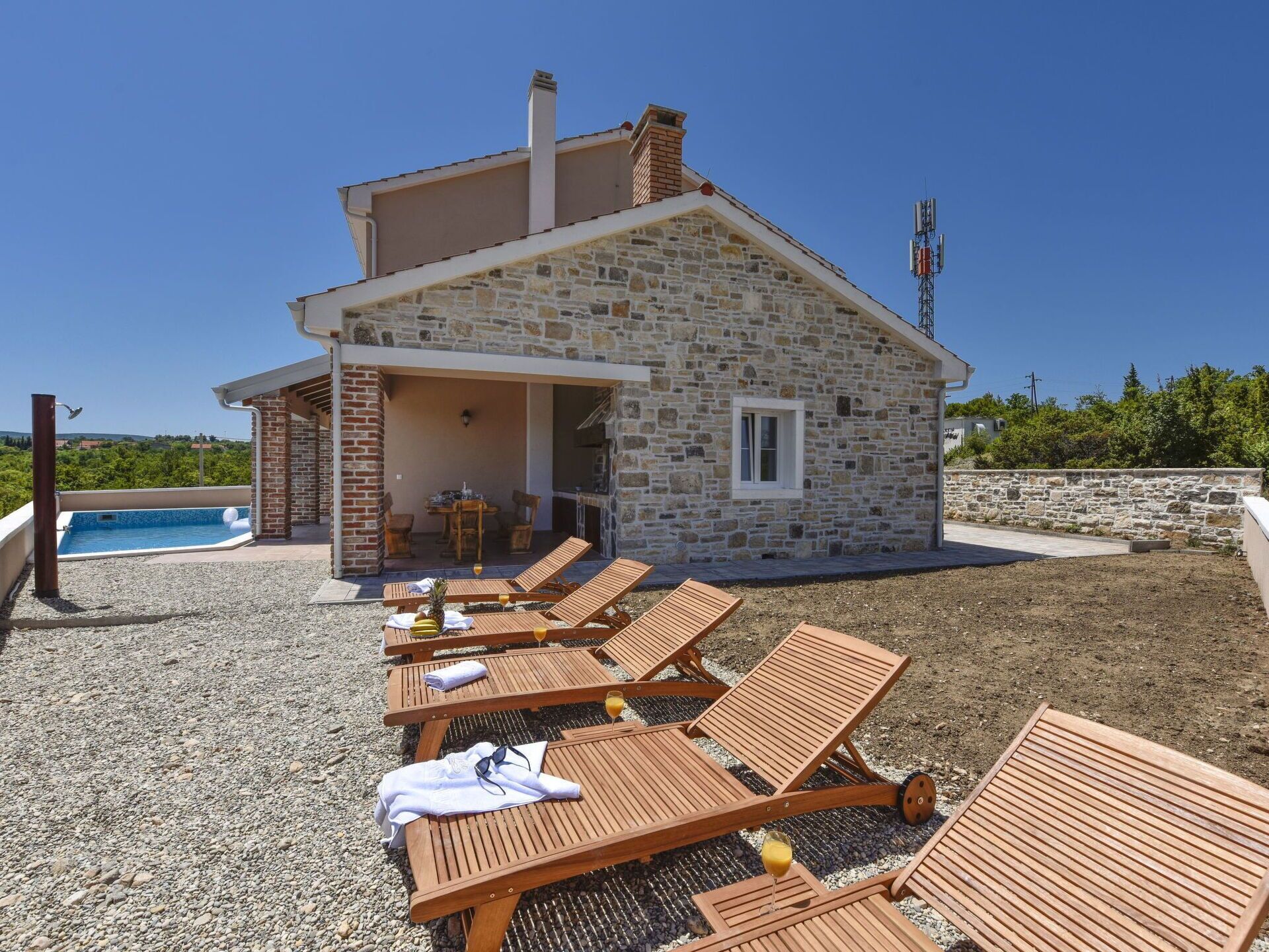 A stone building with a pool and lounge chairs.