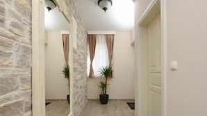 A hallway with stone walls, a wooden floor, and two potted plants.
