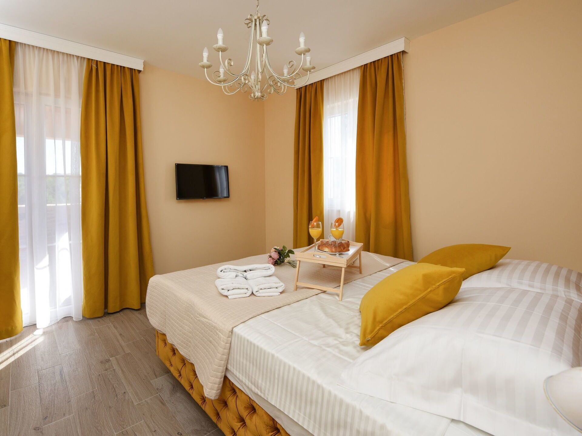 Een hotelkamer met twee bedden, een aan de muur bevestigde televisie en een ontbijtplateau op het bed.