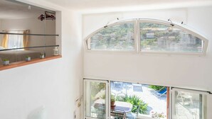 A room with a bed, a window with a view of a hillside, and a balcony with outdoor furniture. - Stunning  villa for 8 guests with A/C, WIFI, TV, terrace and pets allowed (Sanremo)