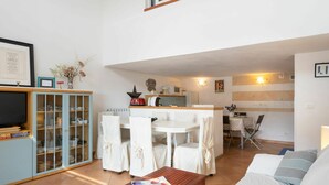 A modern living room with a wooden coffee table, a sofa, and a dining area with a table and chairs. There is a kitchen in the background with a microwave and a toaster. - Stunning  villa for 8 guests with A/C, WIFI, TV, terrace and pets allowed (Sanremo)
