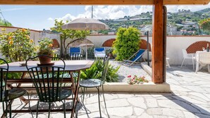 A covered outdoor patio with a table and chairs, a potted plant, and a view of a hillside town. - Stunning  villa for 8 guests with A/C, WIFI, TV, terrace and pets allowed (Sanremo)