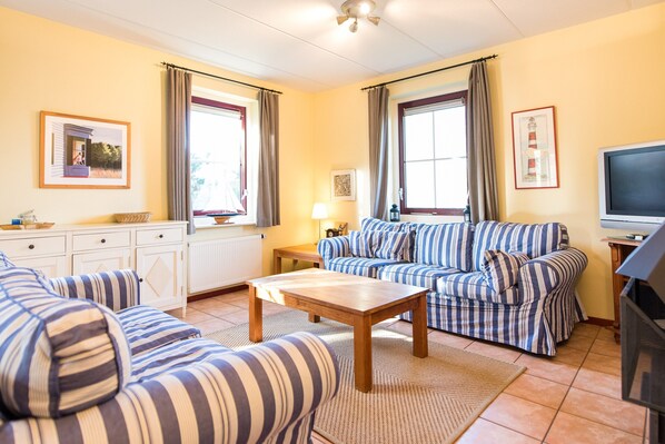 A living room with striped sofas, a wooden coffee table, and a television. - Thatched Villa With Dishwasher Near the Beach (Hollum)