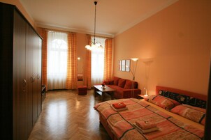 A hotel room with a bed, a sofa, a desk, and a wardrobe.