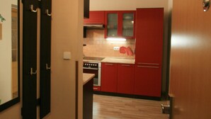 A narrow hallway leading to a kitchen with red cabinets and a stainless steel refrigerator. - Apartment No. 19 Jaltská 3 (Karlovy Vary)