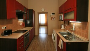 A compact kitchen with red cabinets, a microwave, a washing machine, and a toaster. - Apartment No. 19 Jaltská 3 (Karlovy Vary)