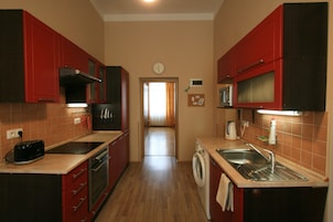 Una cocina compacta con armarios rojos, un microondas, una lavadora y un tostador.