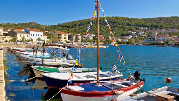 A marina with several boats docked, a wooden pier, and a backdrop of buildings and hills. - Bech Apartment - 4 Persons (Posedarje)