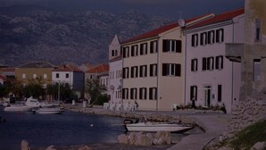 A coastal town with buildings along the waterfront, a dock with boats, and a mountainous backdrop. - Bech Apartment - 4 Persons (Posedarje)