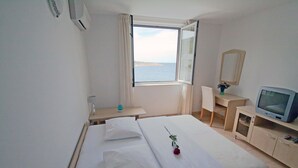 A hotel room with a bed, a desk, a television, and a window with a view of the sea. - Bech Apartment - 4 Persons (Posedarje)