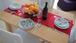 A dining table set with plates, cutlery, a bottle, and a fruit bowl. - Bech Apartment - 4 Persons (Posedarje)