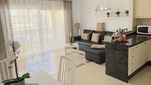Ein modernes Wohnzimmer mit einer Couch, einem Esstisch und einer Küchenzeile.