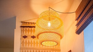 Una sala de estar acogedora con un tapiz decorativo, una lámpara de fibra y un sofá con cojines.