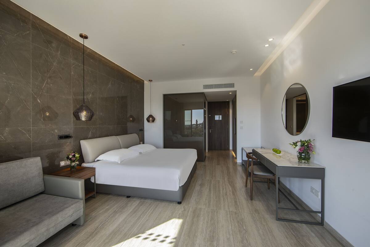 Une chambre d’hôtel moderne équipée d’un lit, d’un canapé, d’un bureau et d’une télévision.