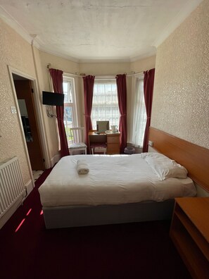 Une chambre d’hôtel avec un grand lit, un bureau, une chaise et un téléviseur fixé au mur.