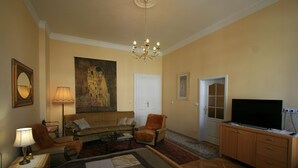 A hotel room with a large bed, a sofa, a chair, a television, and a painting on the wall. - Apartment No. 20 Jaltská 3 (Karlovy Vary)