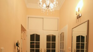 A hallway with a chandelier, double doors, a mirror, and a patterned rug. - Apartment No. 20 Jaltská 3 (Karlovy Vary)