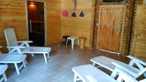 Una cabaña de madera con sillones de plástico blanco y una pequeña mesa.