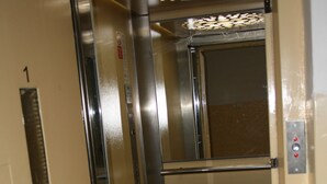 An elevator interior with metallic walls, a door, and a control panel with a red emergency button. - Apartment No. 7 Horova 8 (Karlovy Vary)