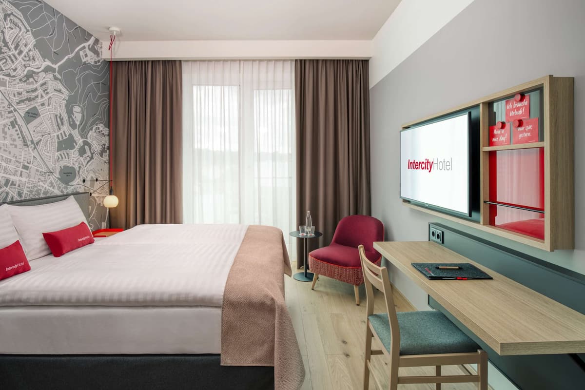 Une chambre d’hôtel avec un lit, un bureau, une chaise, une télévision et une carte accrochée au mur.