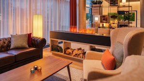 A modern living room with a fireplace, leather sofa, armchair, and a coffee table. - IntercityHotel Saarbrücken (Saarbrücken)