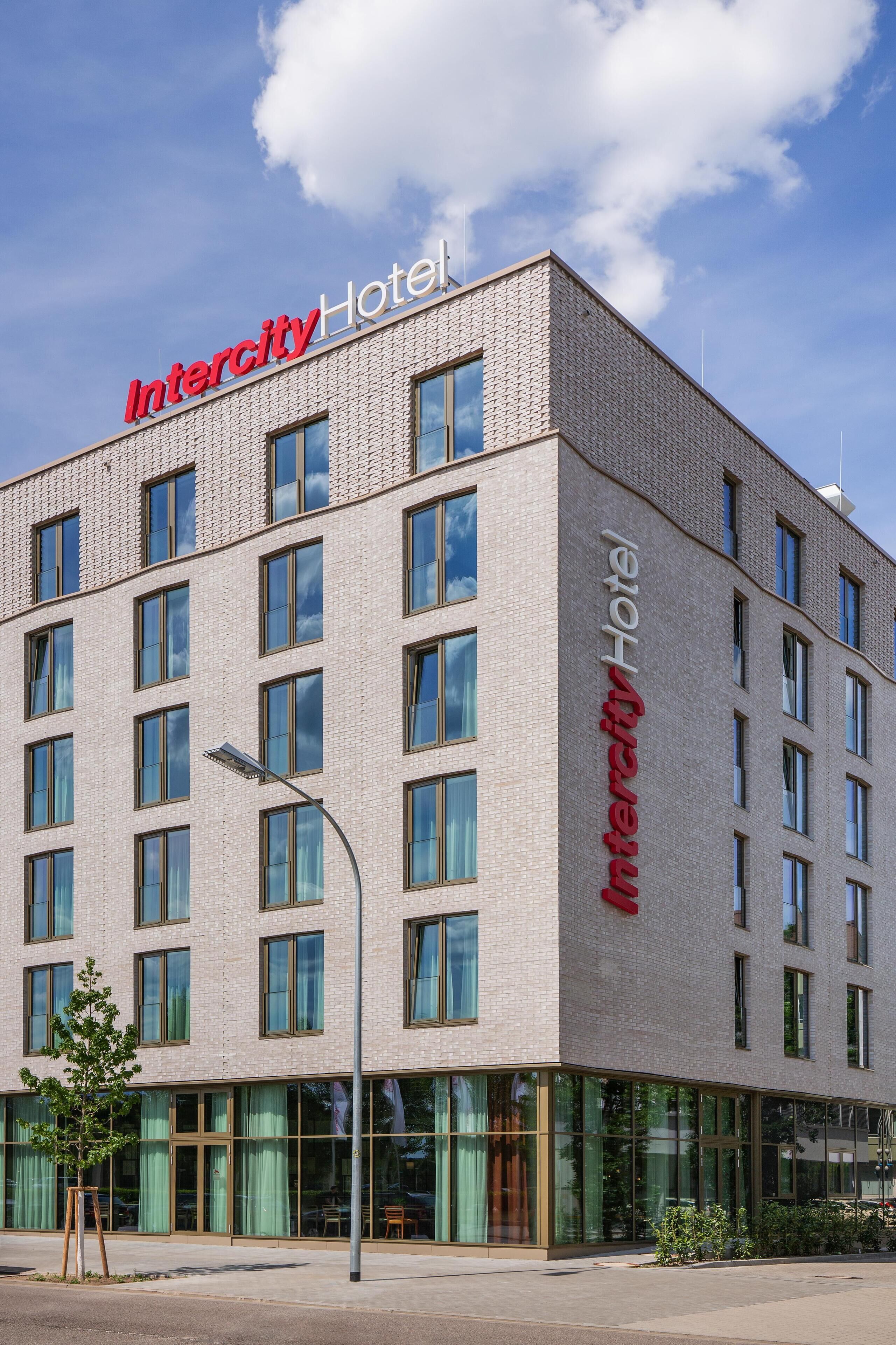 Een modern Intercity Hotel gebouw met een bakstenen gevel, grote ramen en een heldere lucht.