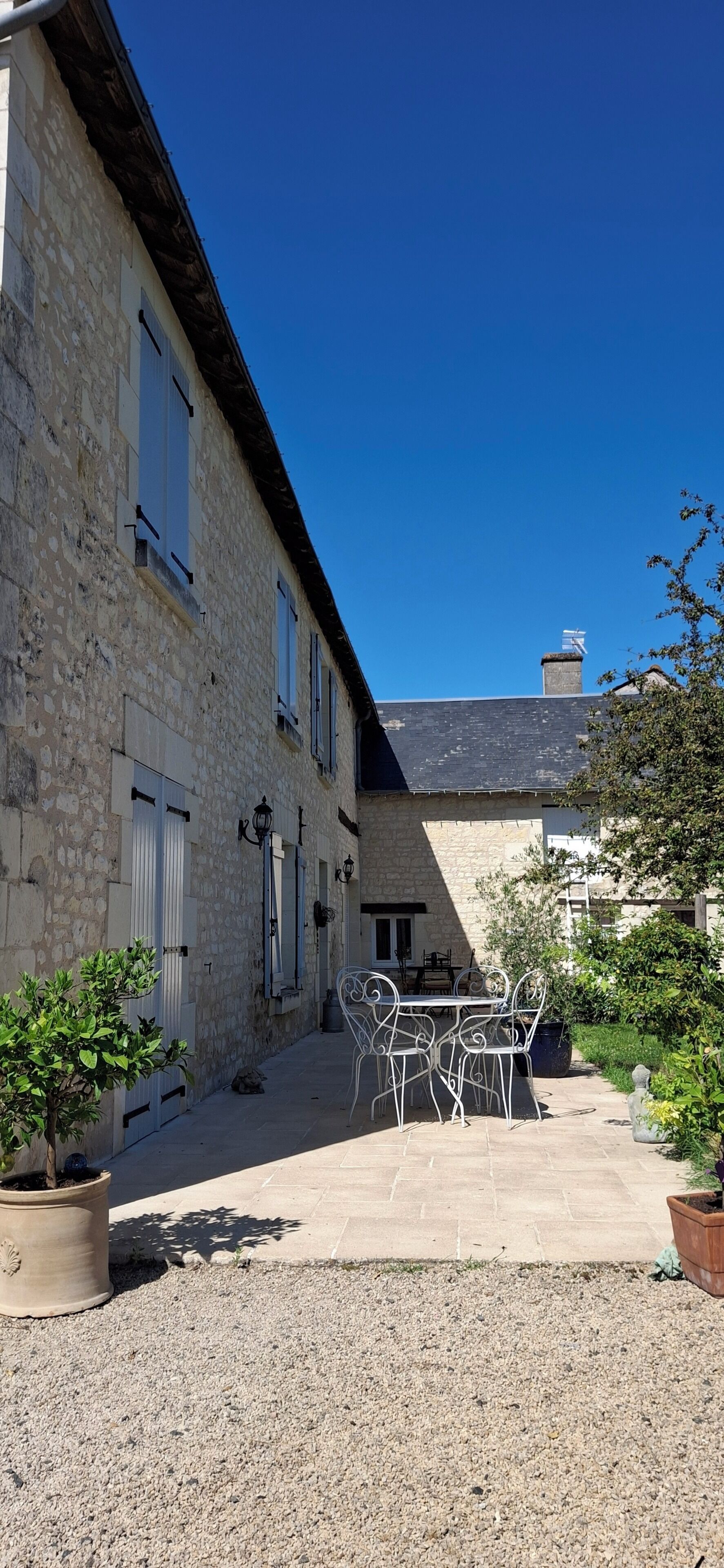 A stone building with multiple windows and a gravel courtyard.