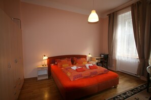 A bedroom with a large bed, bedside tables, a desk, and a window with curtains. - Apartment No. 16A Svahová 14 (Karlovy Vary)