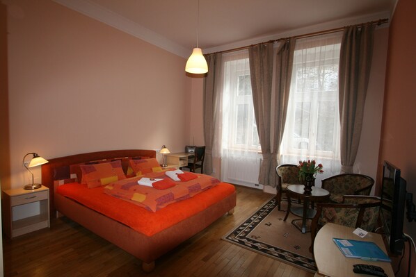 A bedroom with a bed, bedside tables, a desk, and a chair. - Apartment No. 16A Svahová 14 (Karlovy Vary)
