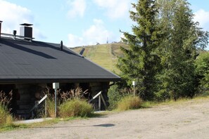 A rustic building with a sloped roof, a chimney, and a gravel driveway. - Rukako Chill Cave (Kuusamo)