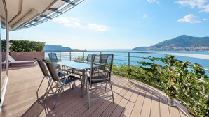 Una terrazza con tavolo e sedie che si affaccia su uno specchio d'acqua e sulla città in lontananza.