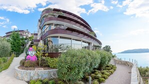 Un edificio moderno a più piani con balconi, un giardino curato e vista sull'acqua.