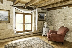 Cozy retreat with exposed beams, stone wall, and a large window.