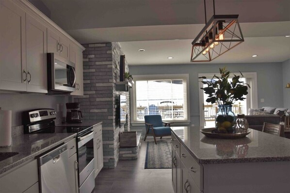 A modern kitchen with a central island, built-in appliances, and a stone accent wall.
