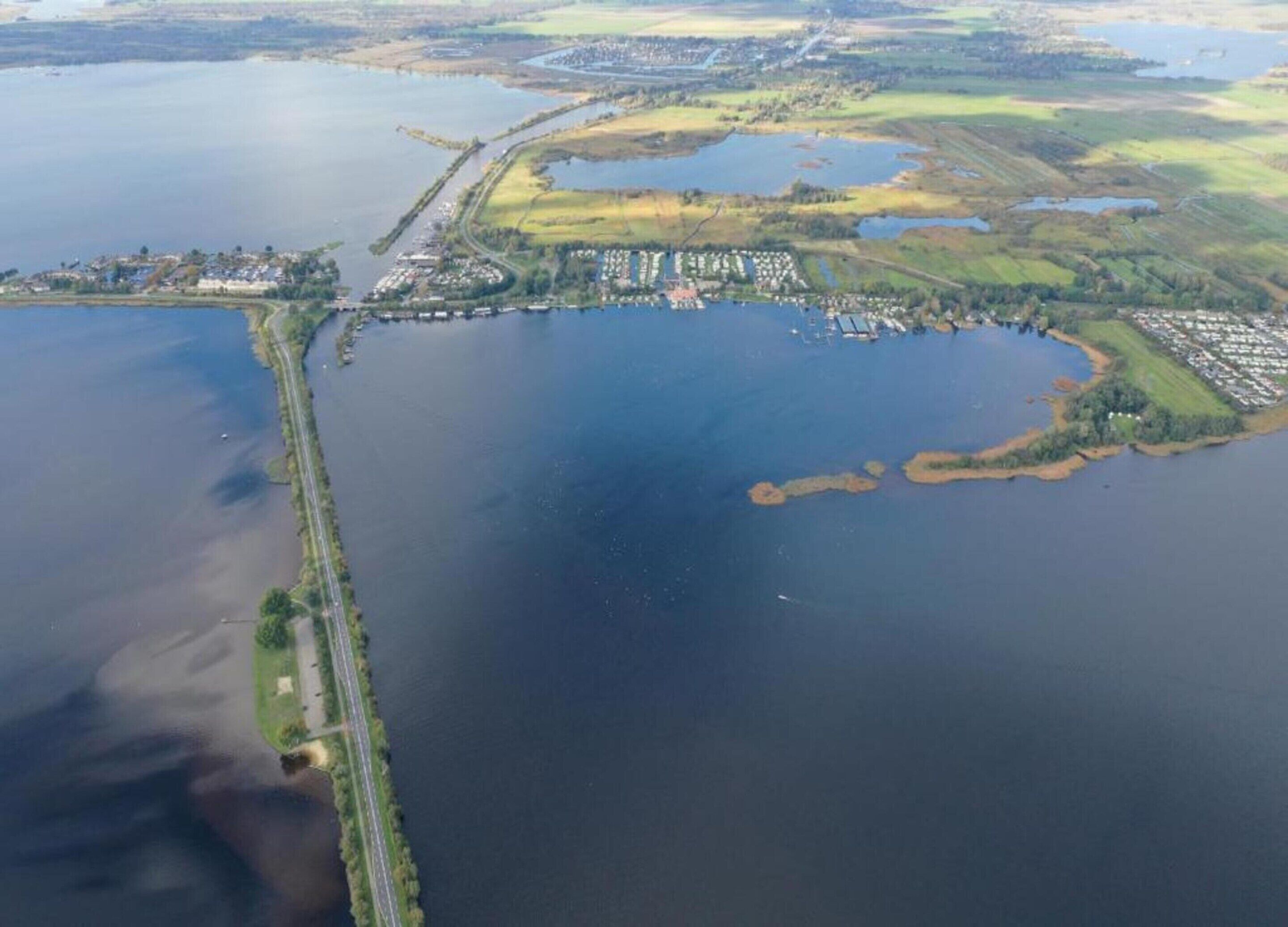 An aerial view of a coastal area with a large body of water, a bridge, and residential buildings.