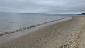 A beach with a wide sandy shore and calm water.