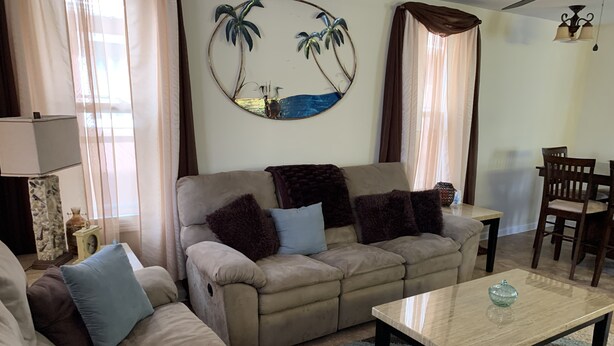 A living room with a beige sofa, a coffee table, and a wall-mounted decorative mirror.