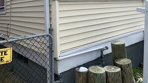 A house with a covered porch, a chain-link fence, and wooden posts.