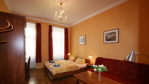 A hotel room with a bed, a sofa, a table with a vase, a chandelier, and two lamps. - Apartment No. 10 Zeyerova 13 (Karlovy Vary)