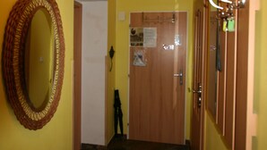 A hallway with yellow walls, a wooden door, and a mirror on the left. - Apartment No. 10 Zeyerova 13 (Karlovy Vary)