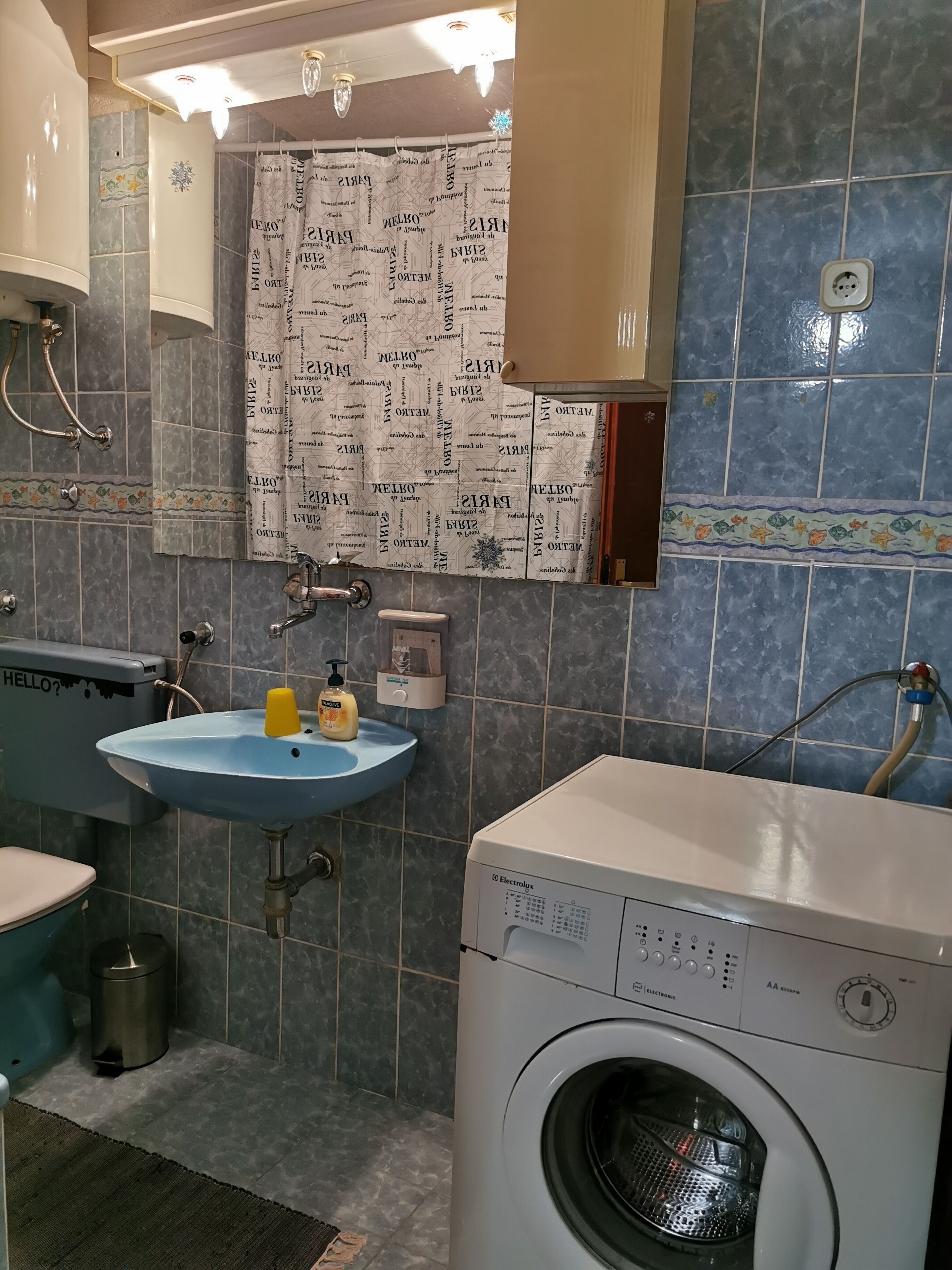 A bathroom with a blue sink, a washing machine, and a shower.