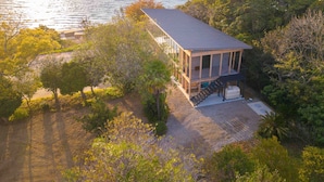 A coastal house with a large balcony overlooking the sea, surrounded by dense vegetation. - Kamome Slow Hotel (Awaji)