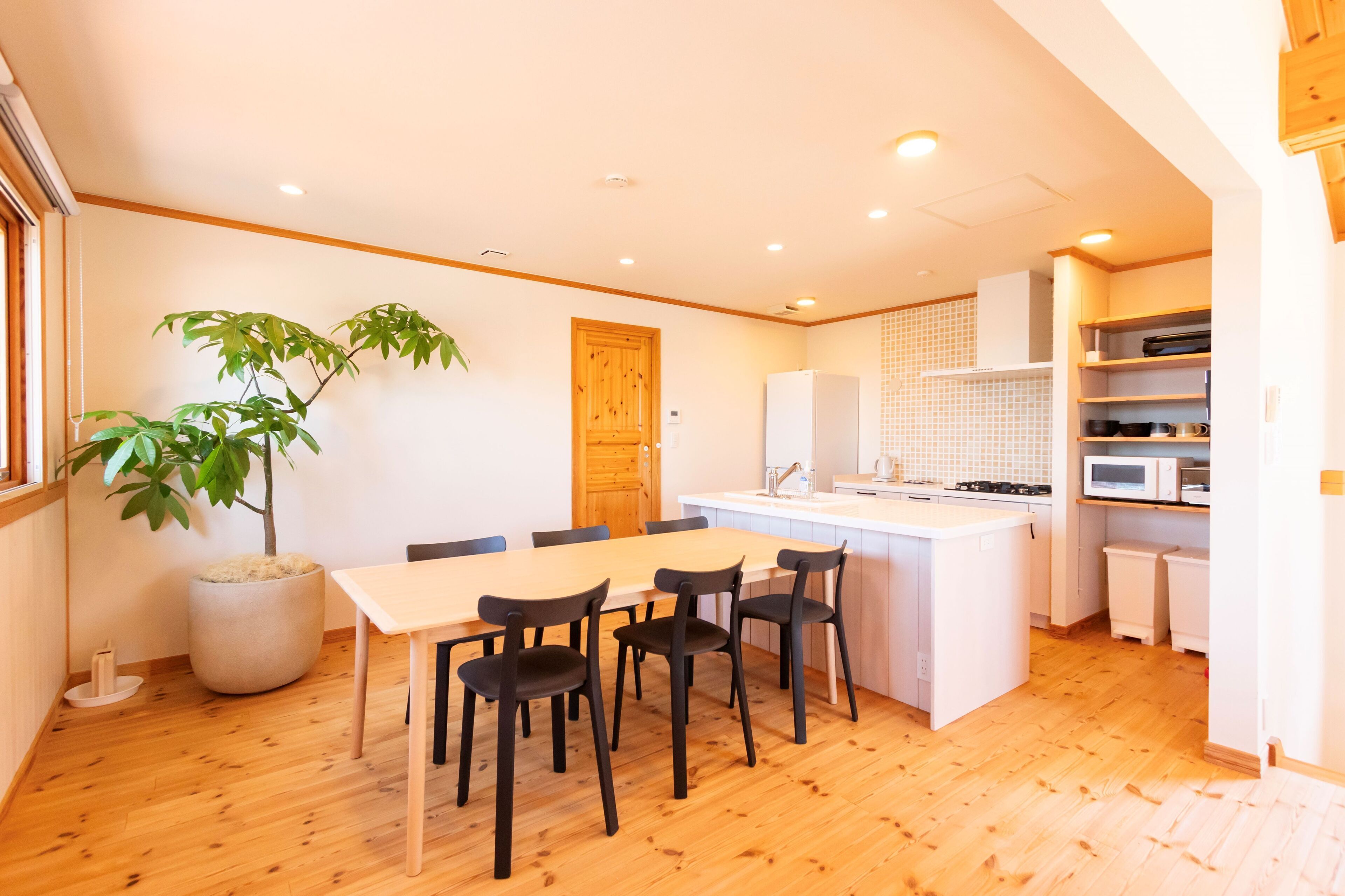 Una cocina moderna con armarios blancos, una isla central y un comedor con mesa y sillas.